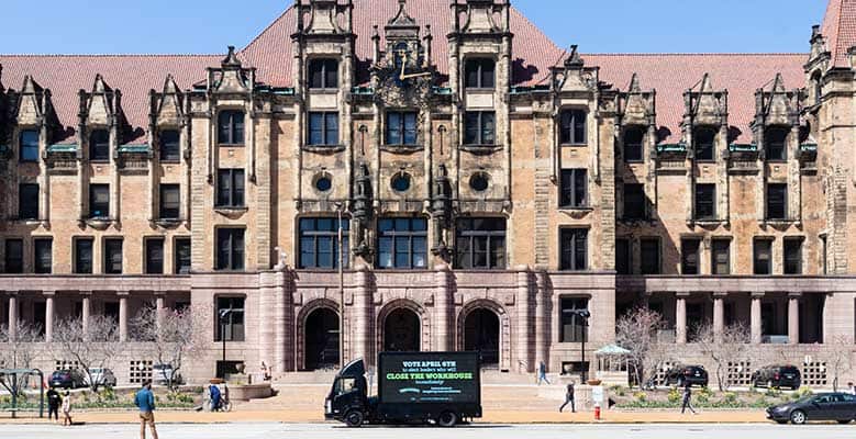 St. Louis city hall with a billboard in front of it that reads, "Vote April 6th for a mayor who will close the Workhouse immediately."
