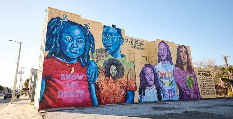 Brandan "Bmike" Odums' mural in Tampa, FL shows 5 young people, each wearing an inspirational shirt, one of which shows Colin Kaepernick. To the right is a list titled "Know Your Rights."